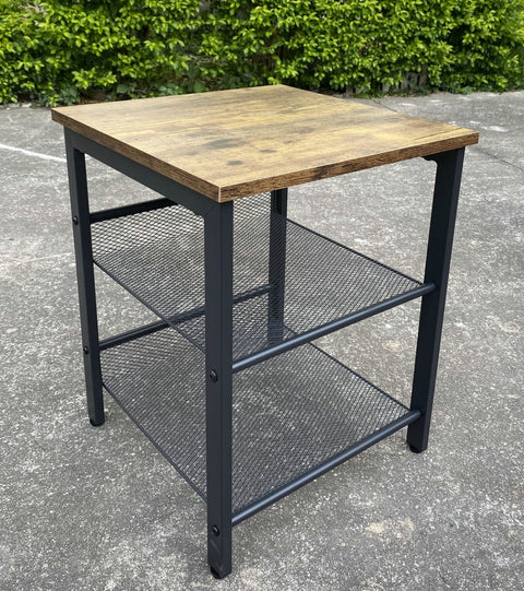Rustic end tables in a cozy living room setting with sofa and lamp
Side View: Square wood top table with black mesh shelf
Angled View: Rustic wood and black metal table with adjustable shelf
Front View: Front profile of industrial end table with wood top and mesh shelf
Top View: Close-up of wood grain tabletop with rounded edges
