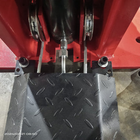 2-post vehicle lift in red installed in garage
Close-up of lifting arms and safety lock mechanism
Base of hoist with truck tires for scale
Top bar and hydraulic system – JH5000F model