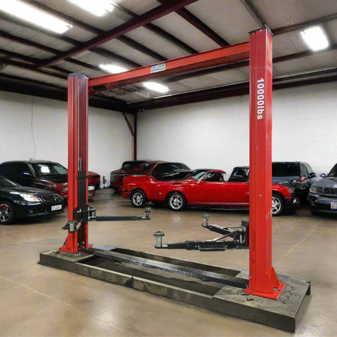 2-post vehicle lift in red installed in garage
Close-up of lifting arms and safety lock mechanism
Base of hoist with truck tires for scale
Top bar and hydraulic system – JH5000F model