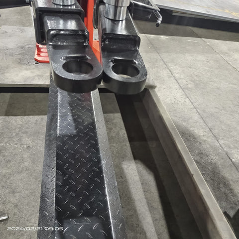 2-post vehicle lift in red installed in garage
Close-up of lifting arms and safety lock mechanism
Base of hoist with truck tires for scale
Top bar and hydraulic system – JH5000F model