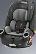 Graco 4Ever 4-in-1 car seat in gray black fabric, angled front view

Graco car seat installation and adjustment positions (4 modes)

Closeup of harness system adjustment knob

Parent placing child in highback booster setup

Side view showing headrest and belt path