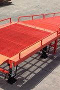 Heavy-duty loading dock ramp with red grating on asphalt yard

Forklift-compatible yard ramp side view with guardrails

Industrial dock ramp base plate and wheels

Side profile of 8 ft wide portable dock ramp

Ramp surface with serrated anti-slip steel close-up