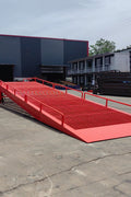 Heavy-duty loading dock ramp with red grating on asphalt yard

Forklift-compatible yard ramp side view with guardrails

Industrial dock ramp base plate and wheels

Side profile of 8 ft wide portable dock ramp

Ramp surface with serrated anti-slip steel close-up