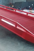 Red 22,000 lb dock ramp showing tread surface and guard rails