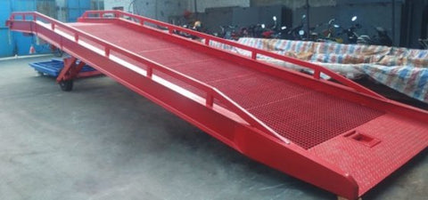 Forklift-compatible heavy-duty portable dock ramp on pavement. Hydraulic lift steel ramp for loading docks and truck beds. Close-up of industrial safety railings on mobile dock platform