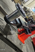 2-post vehicle lift in red installed in garage

Close-up of lifting arms and safety lock mechanism

Base of hoist with truck tires for scale

Top bar and hydraulic system – JH5000F model