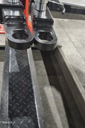 2-post vehicle lift in red installed in garage

Close-up of lifting arms and safety lock mechanism

Base of hoist with truck tires for scale

Top bar and hydraulic system – JH5000F model