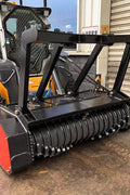 Skid Steer Drum Mulcher with heavy-duty drum and black housing

Second Image: Mounted rotary slasher on skid steer for brush cutting

Third Image: Close-up view of reinforced rotor and cutting teeth

Fourth Image: Side profile of attachment with connection points
