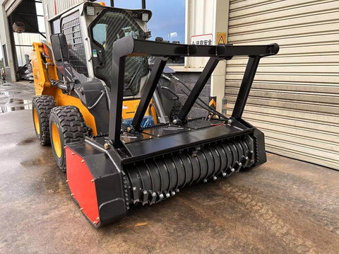 Skid Steer Drum Mulcher with heavy-duty drum and black housing

Second Image: Mounted rotary slasher on skid steer for brush cutting

Third Image: Close-up view of reinforced rotor and cutting teeth

Fourth Image: Side profile of attachment with connection points