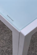 White glass dining table set with 4 chairs in the bright kitchen
Close-up of white glass table and upholstered chair
Side angle of a full 5-piece dining set
White dining chairs around a modern glass table
Dining set outdoors showing full product design